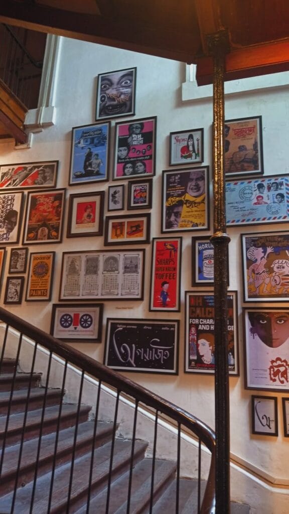 A staircase wall covered in a dense gallery of framed vintage-style posters, advertisements, and film graphics.