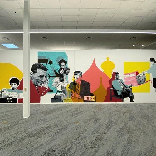 A long office wall featuring a mural with vintage-style illustrations of people working, a jet, and architectural shapes in a warm color palette.