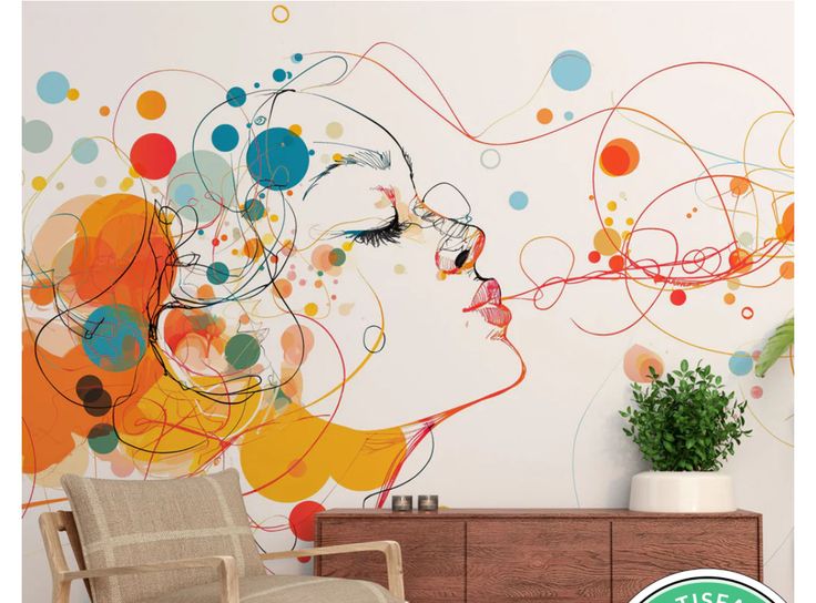 A large-scale wall mural featuring a line-art profile of a woman’s face. She is surrounded by a playful explosion of colorful circles and swirling lines in orange, red, and blue. The mural is set in a room with a wooden sideboard and a mid-century modern chair.