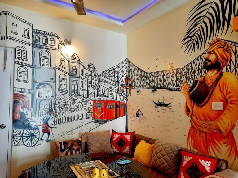 Hand-painted Kolkata city mural featuring Howrah Bridge, tram, rickshaw, and cultural figure wall art in a modern living room.