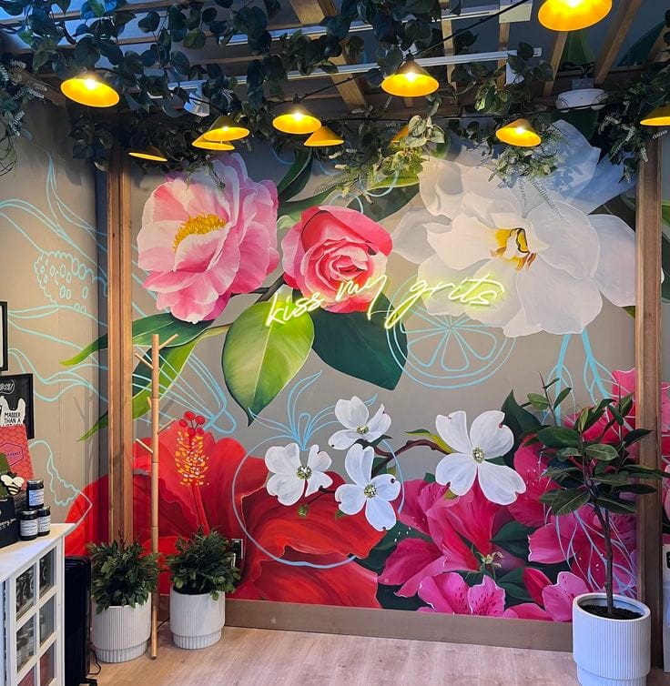 Floral wall mural with large pink and white flowers inside a modern café interior by Oikar Studio